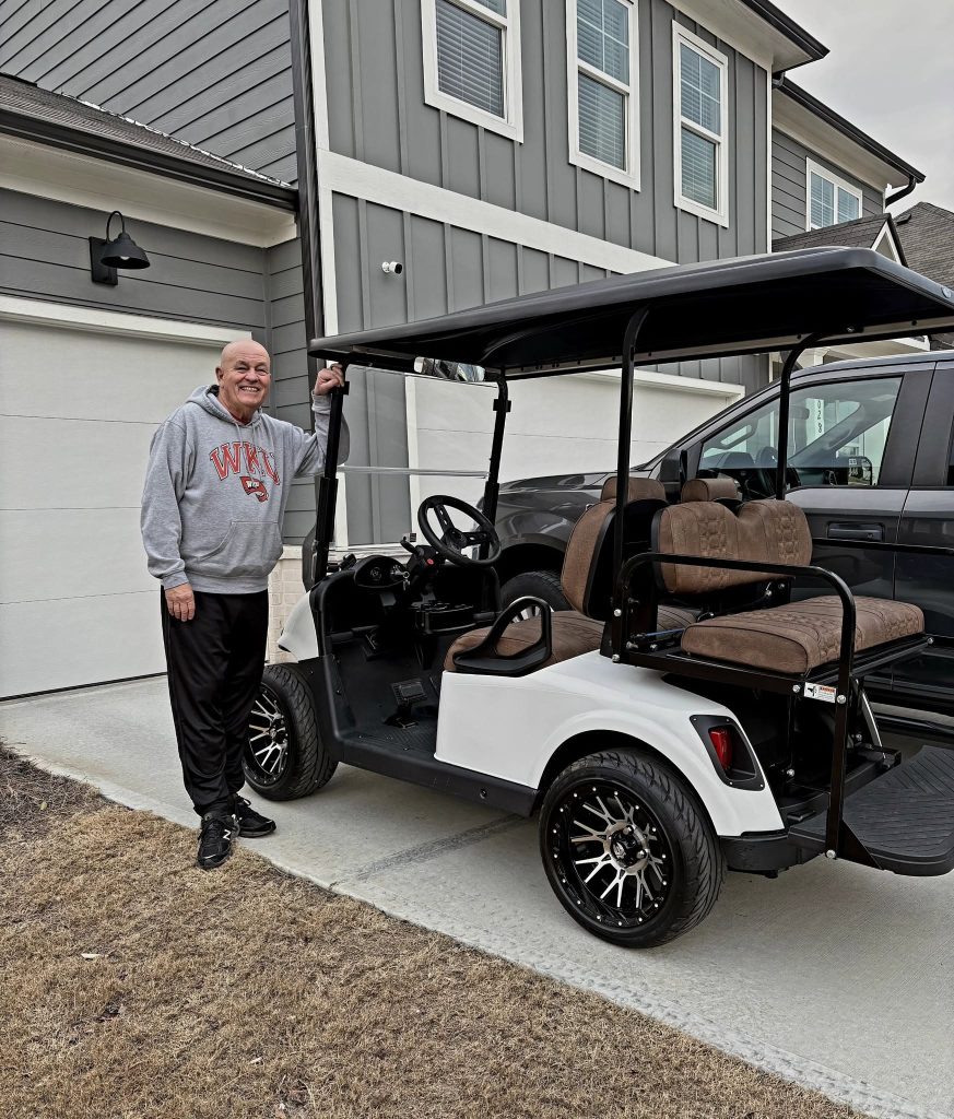 Customer with new white golf cart in driveway